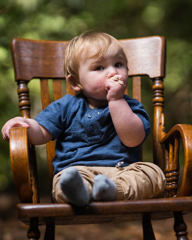 Happy baby celebrating a milestone moment — first birthday cake smash photography